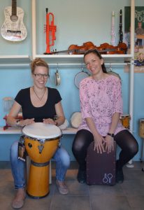 To kvinder spiller tromme i musikbutik